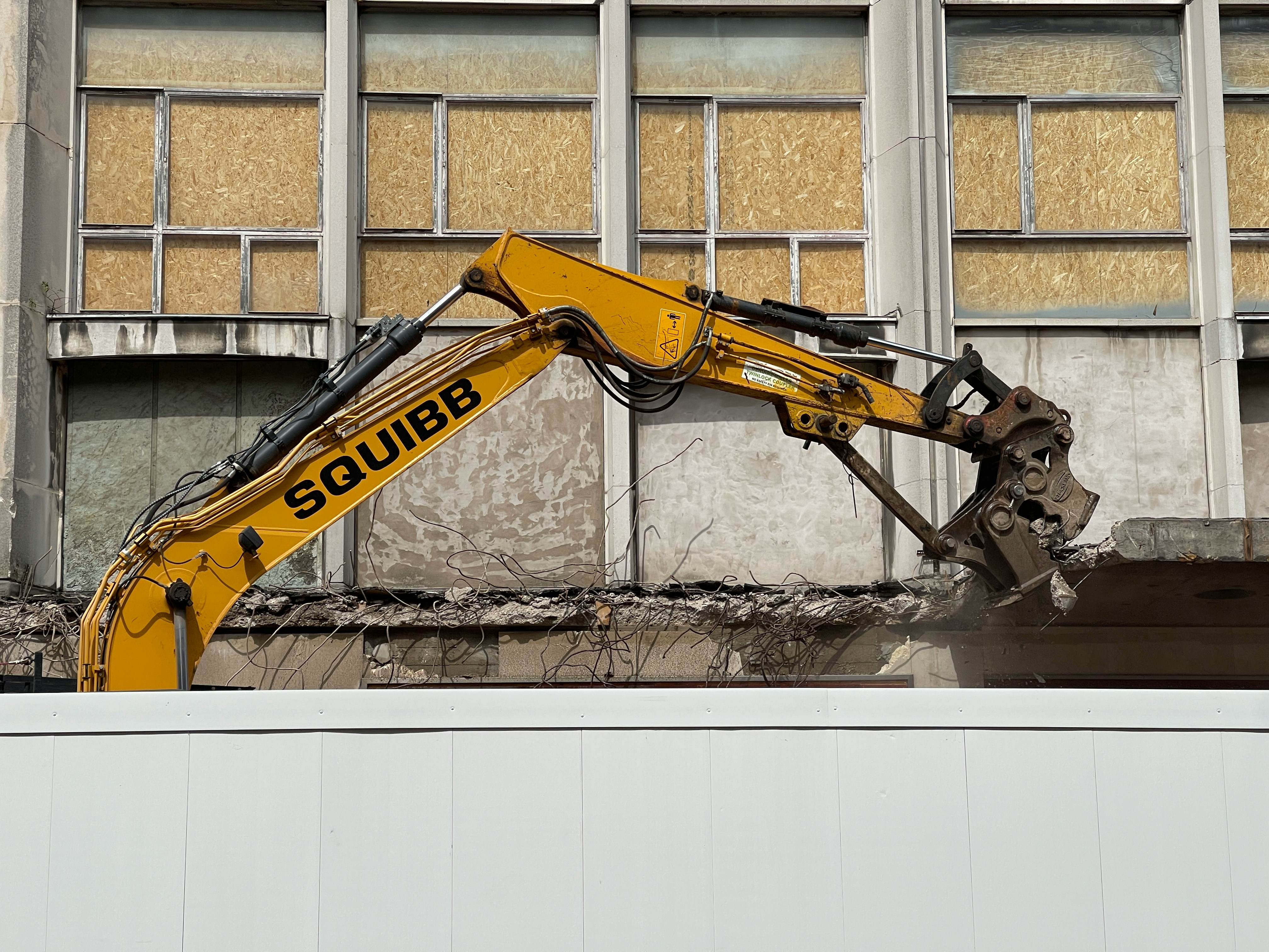 Excavator demolishing a building facade during structural construction works