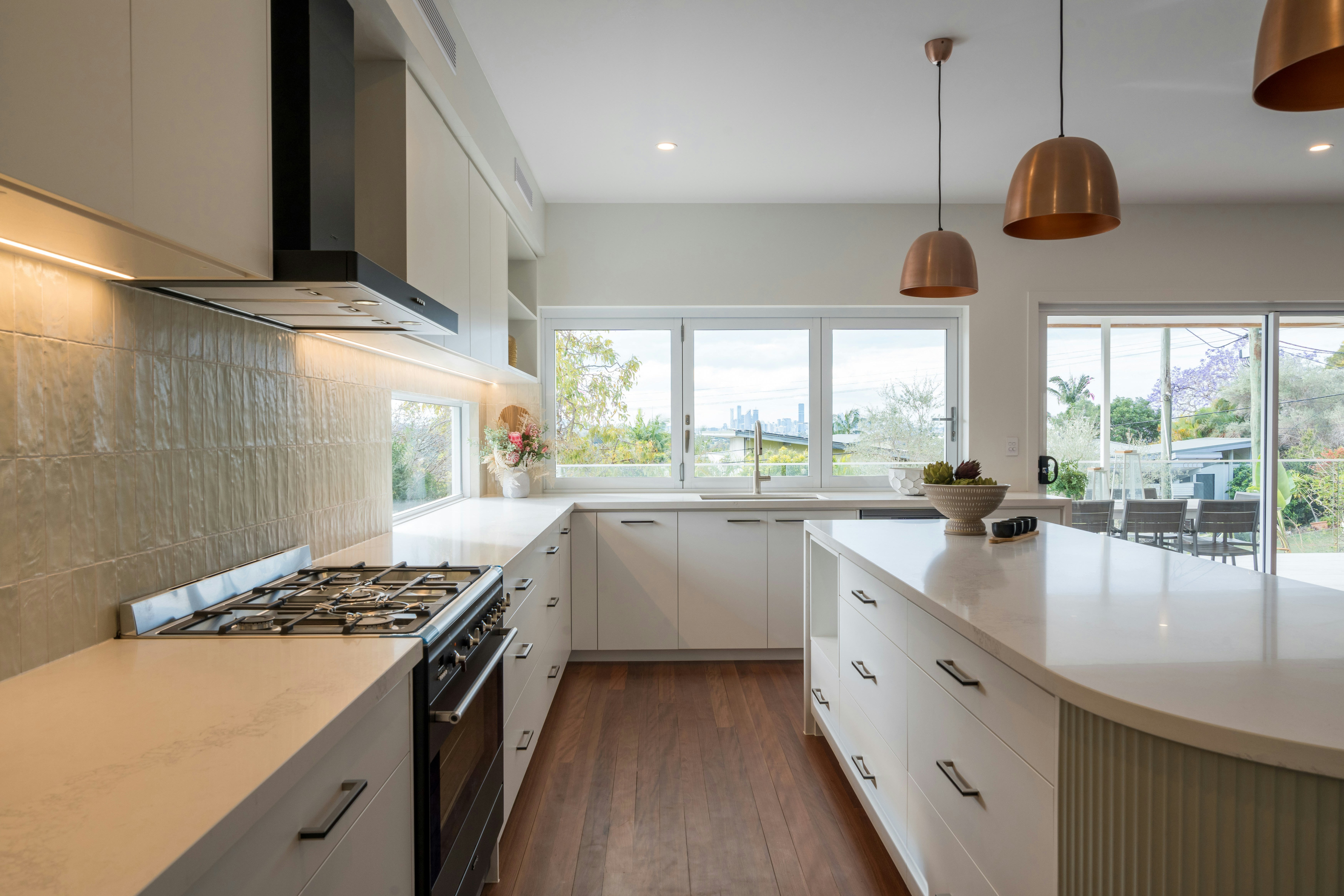 Modern white kitchen with copper pendant lights after full refurbishment